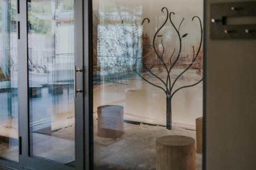 eine Glastür mit einer Baumskulptur in der Unterkunft G'sund & Natur Hotel Die Wasnerin - Adults Only in Bad Aussee