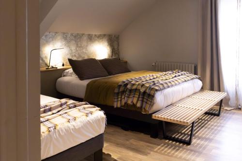 a bedroom with two beds and a bench in it at Hotel Linette in Aumont-Aubrac