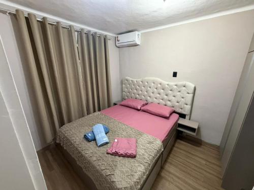 a small bedroom with a bed with pink and pink sheets at Casa aconchegante em Olaria in Nova Friburgo