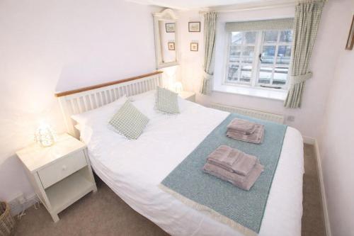 ein Schlafzimmer mit einem weißen Bett, auf dem zwei Handtücher liegen in der Unterkunft Brookside, Hawkshead with garden and parking in popular village in Hawkshead