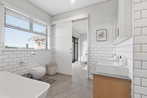 a white bathroom with a sink and a toilet at Yellow-tail Room in Ballito