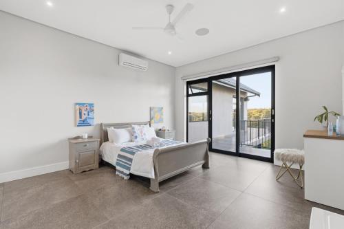 a bedroom with a bed and a sliding glass door at Yellow-tail Room in Ballito