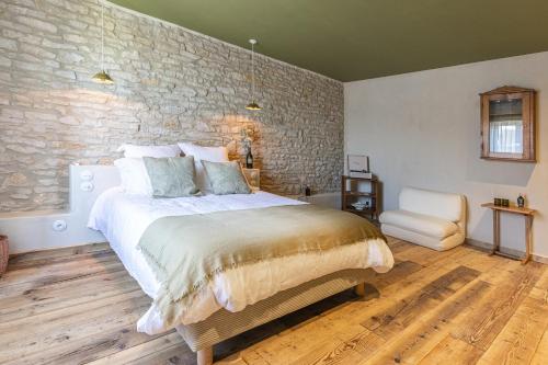 a bedroom with a bed and a stone wall at La Chaumée par L'émulsion in Saint-Alban-de-Roche