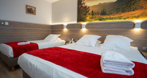 a hotel room with two beds with red and white sheets at Hotel Restaurant Au Parc des Cigognes in Kintzheim