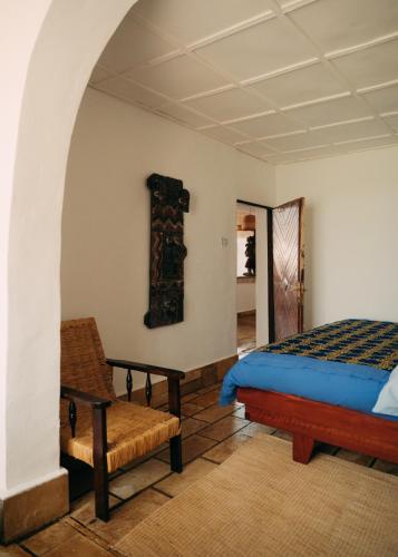 a bedroom with a bed and a chair at Rwanda African Art Museum in Nyabisindu