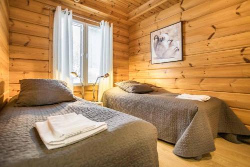 two beds in a room with wooden walls at Päijänteen Helmi 2 in Jämsä