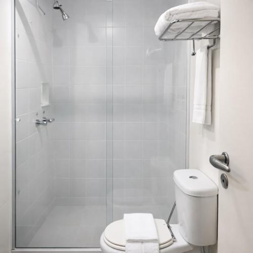 a white bathroom with a toilet and a shower at Flat próximo ao Aeroporto Congonhas Piscina, Academia e Restaurante in São Paulo
