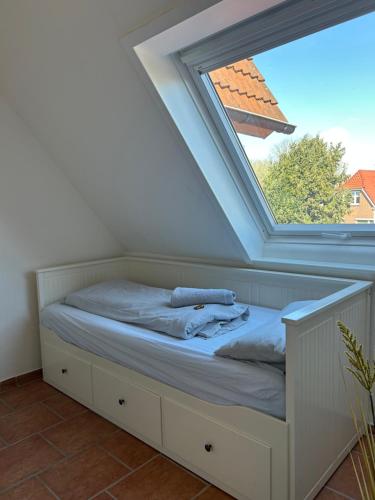 a bed in a room with a window at Fewo Schröder - BUDE 63a - mit Strandkorb am Meer - inklusive Bettwäsche und Handtücher in Westerdeichstrich