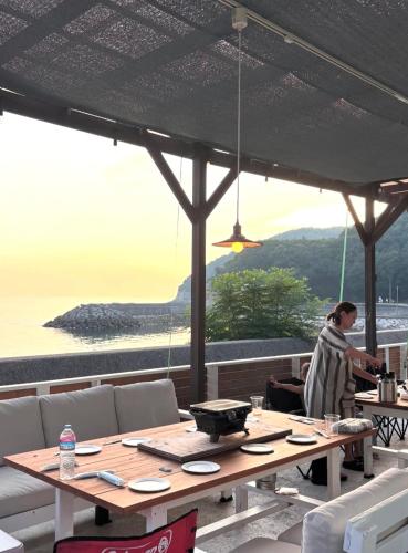 a woman sitting at a table with a view of the ocean at プチリゾート・ひじきwest in Hijiki
