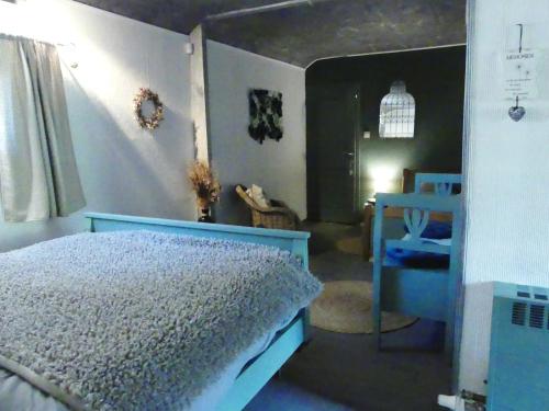 a bedroom with a blue bed and a table at Suite romance in Froid-Chapelle
