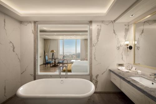 a bathroom with a tub and a sink and a bedroom at The Greenberry Mountain Resort Narkanda in Nārkanda