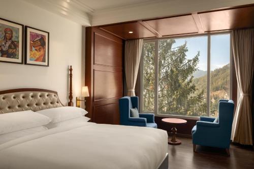 a hotel room with a bed and two chairs and a window at The Greenberry Mountain Resort Narkanda in Nārkanda
