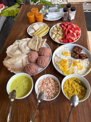 a wooden table with plates of breakfast foods and spoons at Wanora Eco Villa in Dickwella