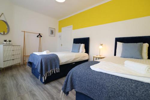 a hotel room with two beds with blue and yellow walls at Signature - Bueno View - Greenock in Greenock