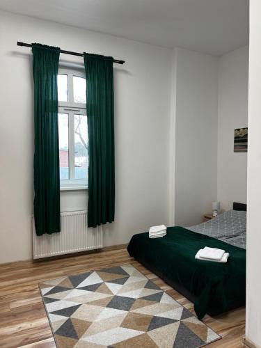 a bedroom with green curtains and a bed with a rug at Noclegi Korzybie in Korzybie