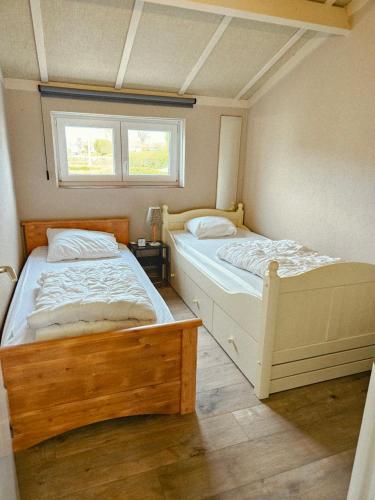 two beds in a small bedroom with a window at Duinenhuis Zeepolder 27 in De Haan