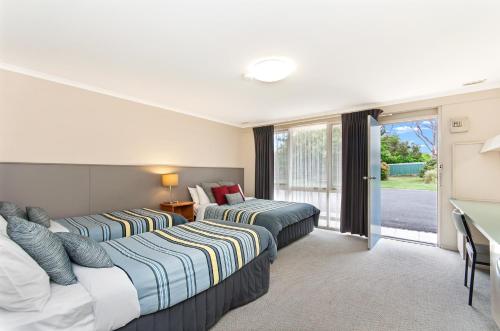 a hotel room with two beds and a desk at Melaleuca Motel in Portland