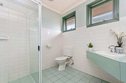 a bathroom with a toilet and a sink and a shower at Melaleuca Motel in Portland