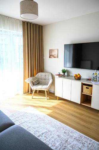 a living room with a large television and a chair at Miamare Dziwnow - Komfort Apartment, Panorama, Beach, Pool & Wellness in Dziwnów