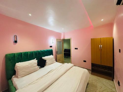 a bedroom with a large bed with pink walls at FortExcel Hotels & Suites in Odogun