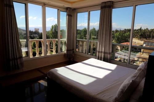 a bedroom with a bed in front of a large window at Kanaan Group Hotel in Baalbeck