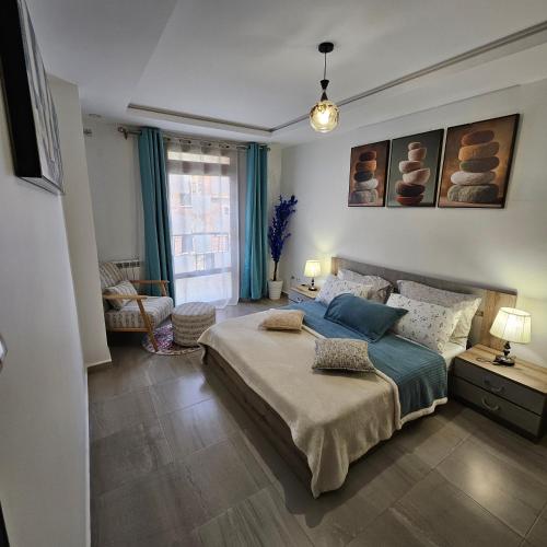 a bedroom with a large bed with blue pillows at Beau F3 in Dar el Beïda
