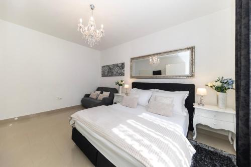 a white bedroom with a large bed and a chandelier at Central Square Luxury Boutique in Zadar