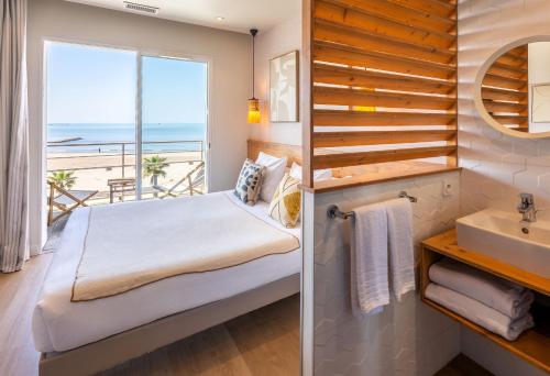 a bathroom with a bed and a view of the ocean at Hôtel Café Miramar in Le Grau-du-Roi