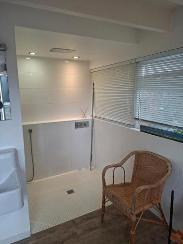 a bathroom with a chair and a tub and a sink at Studio Les 4 Vents in Tréffiagat