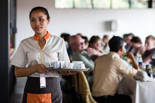 a woman holding a tray of cups and saucers at Sala Baï Hotel & Restaurant School in Siem Reap