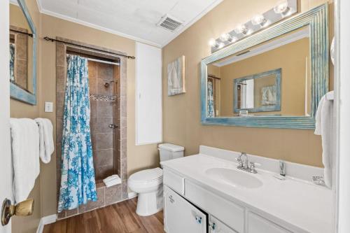 a bathroom with a sink and a toilet and a mirror at Sunny Beach by Book That Condo in Panama City Beach