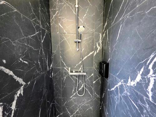 a shower in a bathroom with black marble walls at Duplex Cosy proche parlement européen et Strasbourg in Schiltigheim