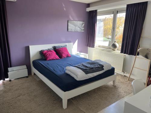 a bedroom with purple walls and a bed with pink pillows at Casa Leopardo in Hasselt