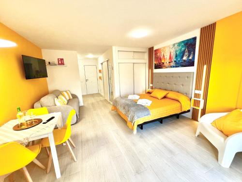 a room with two beds and a couch and a table at Modern Studio with Pool & Terrace Playa de las Américas, Tenerife in Playa de las Americas