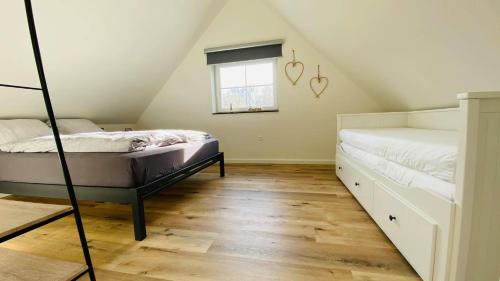 a attic bedroom with two beds and a window at Vakantiewoning d'Hoppe in Flobecq