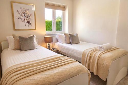 two beds in a room with a window at Horizon House, Luxury 2-Bedroom Ground floor flat, Parking, WiFi, Netflix in Oxford