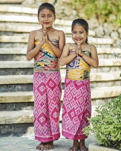 two young girls standing in front of some steps praying at Four Seasons Resort Bali at Jimbaran Bay in Jimbaran