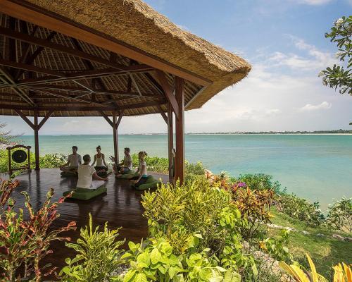 a group of people sitting under a pavilion by the ocean at Four Seasons Resort Bali at Jimbaran Bay in Jimbaran