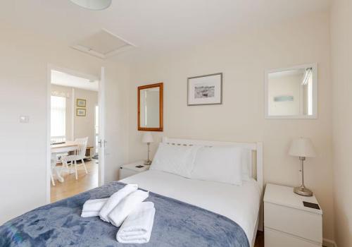 a white bedroom with a bed with towels on it at Highview, extended 2 bedroom house, with view, near coast path in The Mumbles