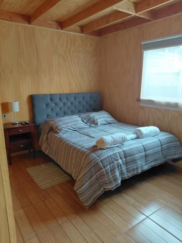 a bedroom with a bed with a blue headboard and a window at Los Gladiolos in Melipeuco