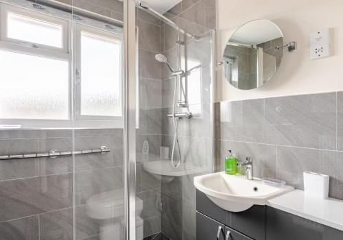 a bathroom with a shower and a sink and a mirror at Highview, extended 2 bedroom house, with view, near coast path in The Mumbles