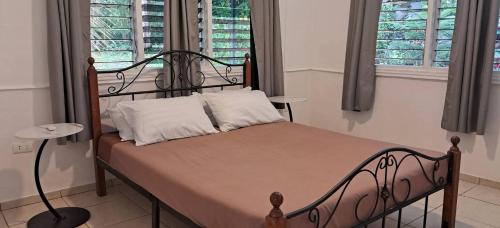 ein Schlafzimmer mit einem Bett mit Metallrahmen und zwei Fenstern in der Unterkunft Jean Homestay in Siquijor