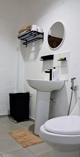 ein Badezimmer mit weißer Toilette und Spiegel in der Unterkunft Jean Homestay in Siquijor