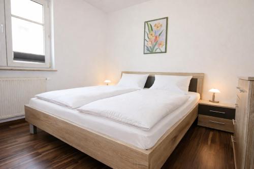 a bedroom with a large bed with white sheets and a window at Strandschlösschen in Kühlungsborn