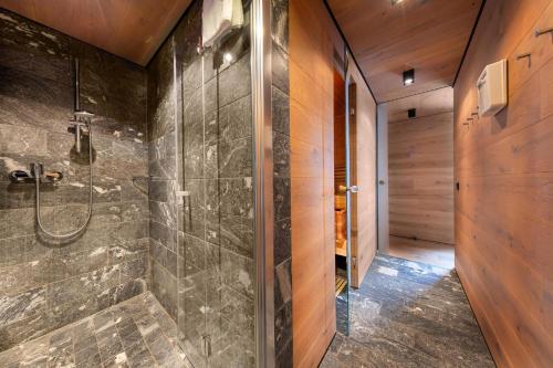 a walk in shower in a bathroom with wooden walls at Smaragdresort Chalet Bergblick in Bramberg am Wildkogel