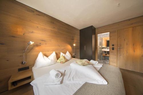 a bedroom with a bed with white sheets and pillows at Smaragdresort Chalet Bergblick in Bramberg am Wildkogel