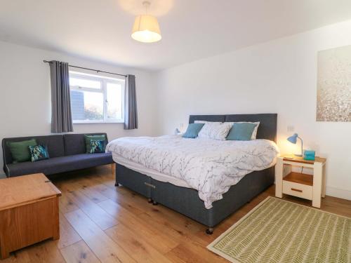 a bedroom with a large bed and a couch at Snowdrop Cottage in Maidstone