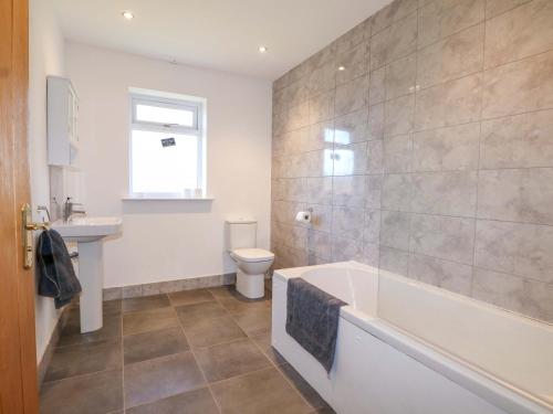 a bathroom with a tub and a toilet and a sink at Snowdrop Cottage in Maidstone