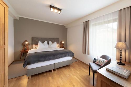 a bedroom with a bed and a chair and a window at Seehaus Verena in Weissensee