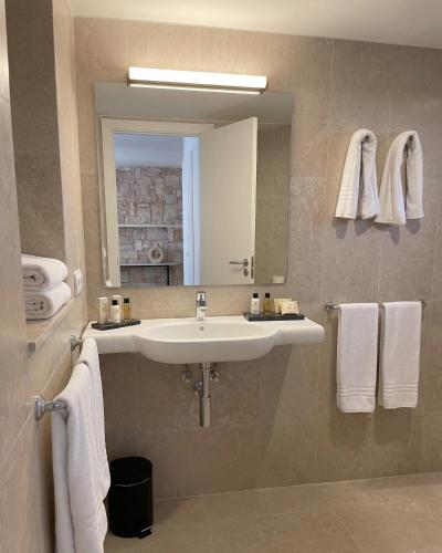 a bathroom with a sink and a mirror and towels at Hotel Xaloc Playa in Punta Prima